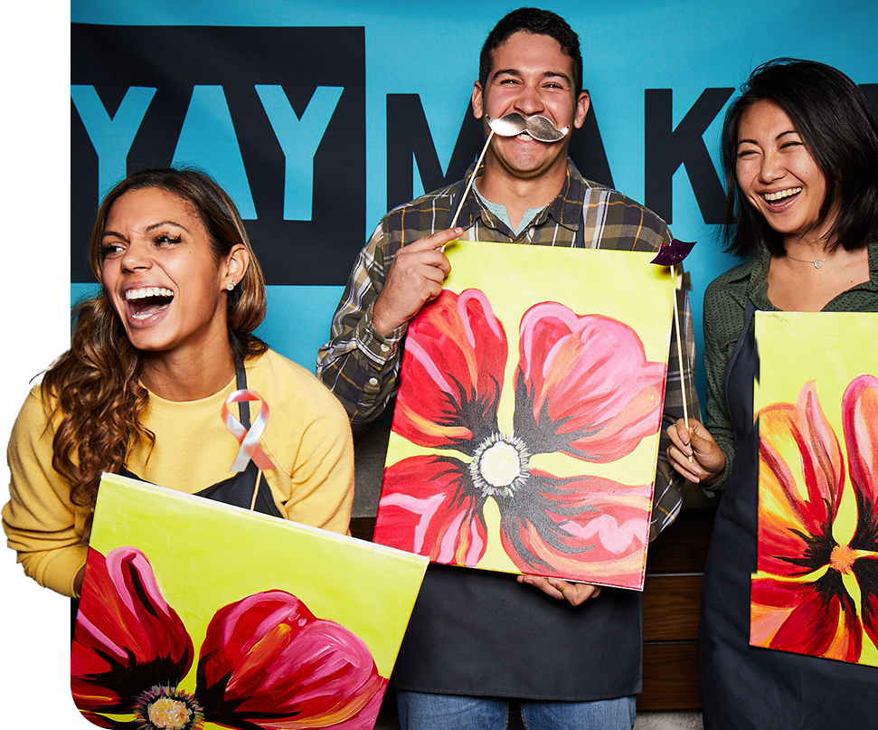 three friends smiling with painted canvases at paint night fundraiser